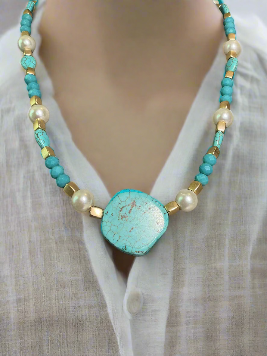 A turquoise, gold and pearl beaded necklace with large turquoise bead focal point