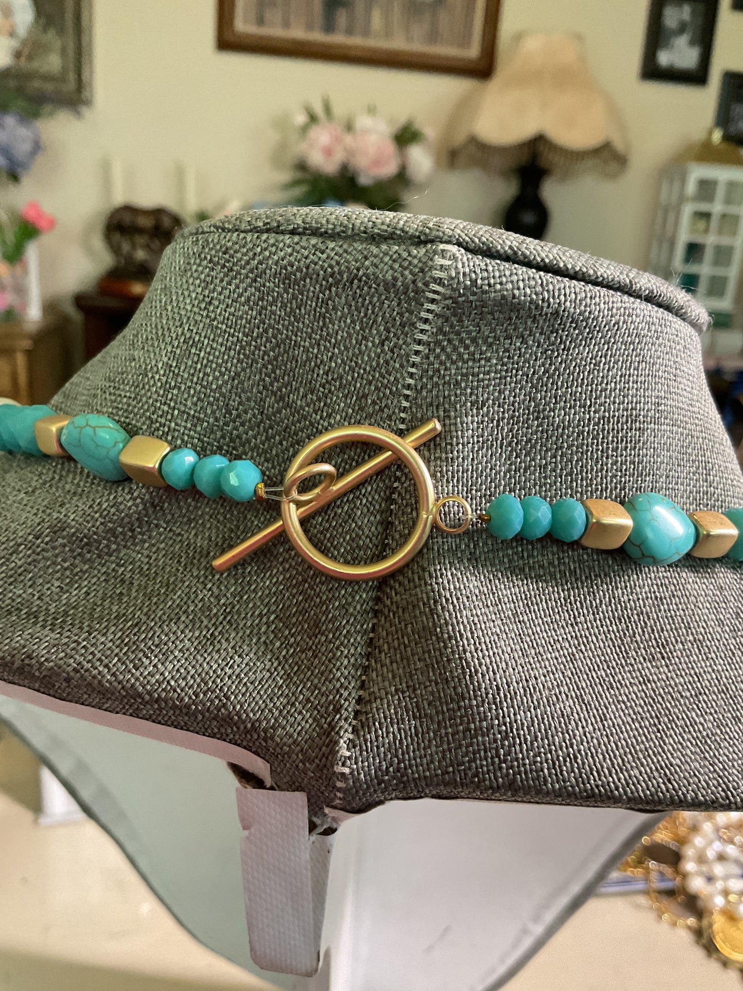 A turquoise, gold and pearl beaded necklace with large turquoise bead focal point
