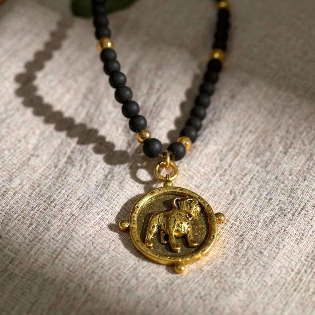 A black and gold beaded necklace with a Bulldog pendant