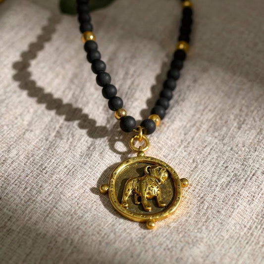 A black and gold beaded necklace with a Bulldog pendant