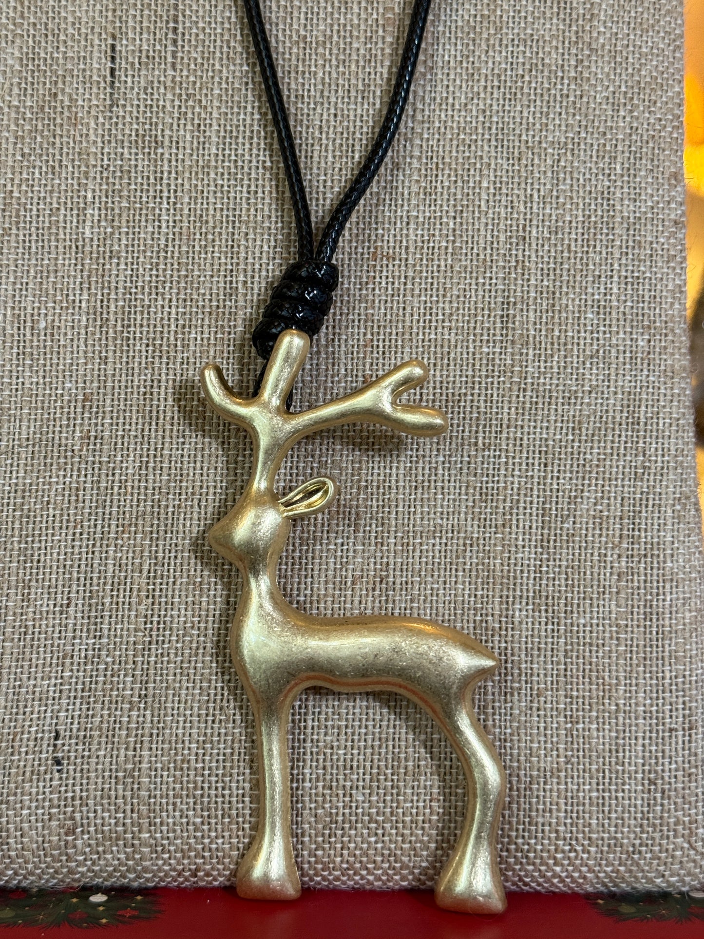Large matt gold reindeer pendant on a black cord necklace