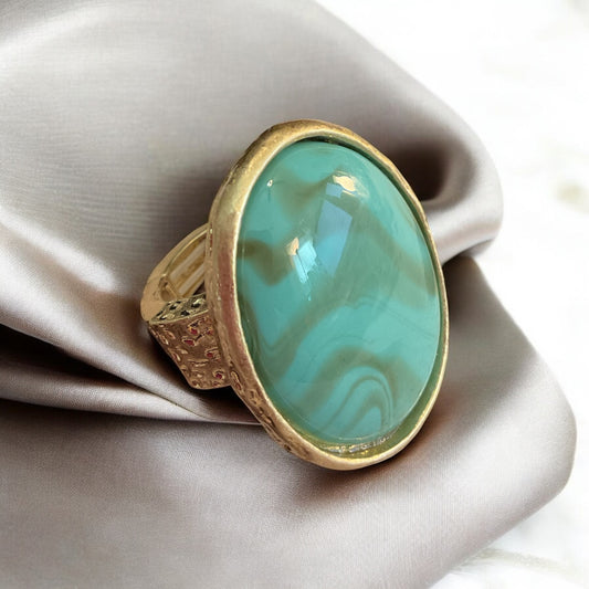 Large turquoise color stone set in gold stretch ring