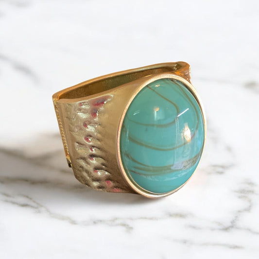 Large turquoise color stone set in a wide gold clamp bracelet
