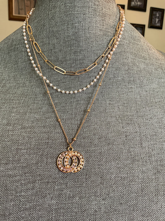 Multi layer necklace with interlocking circle, pendant and dainty pearls